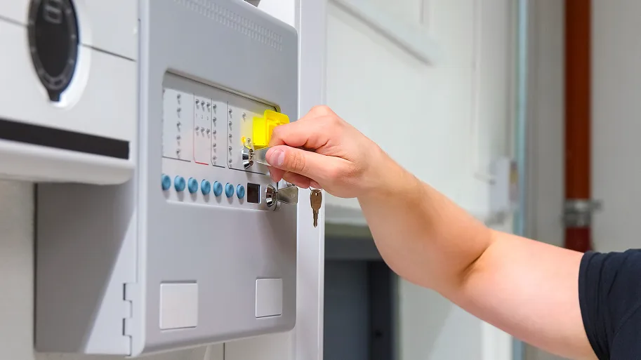 Elektroniker der mit einem Schlüssel eine Anlage scharf schaltet